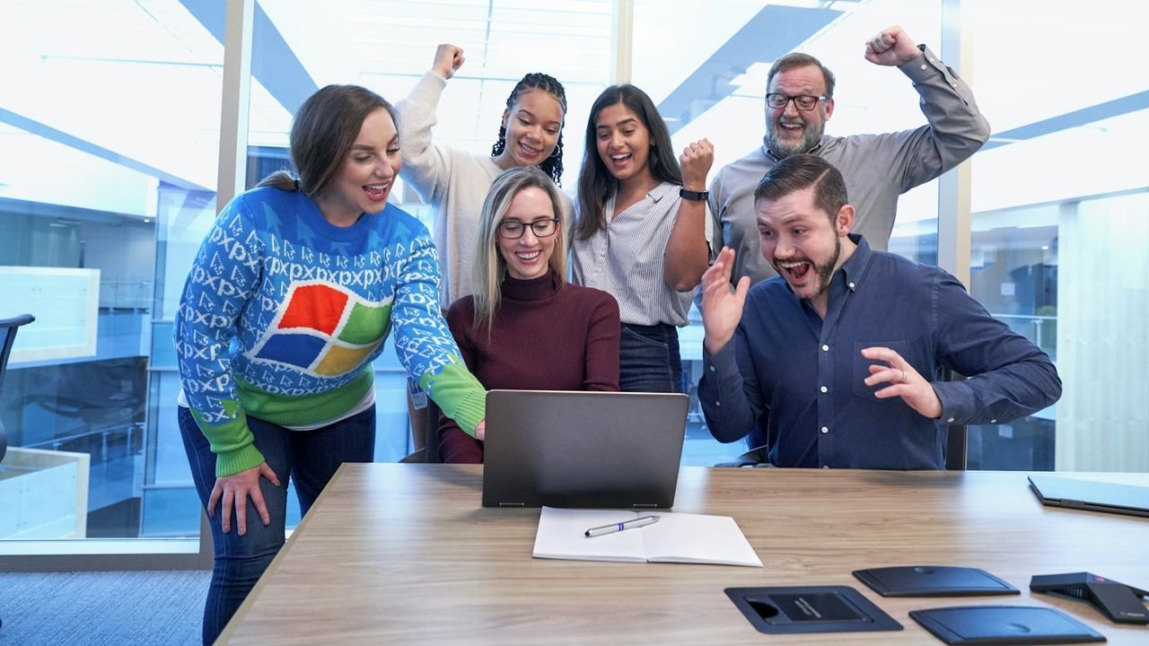 Happy small team gathered around a laptop