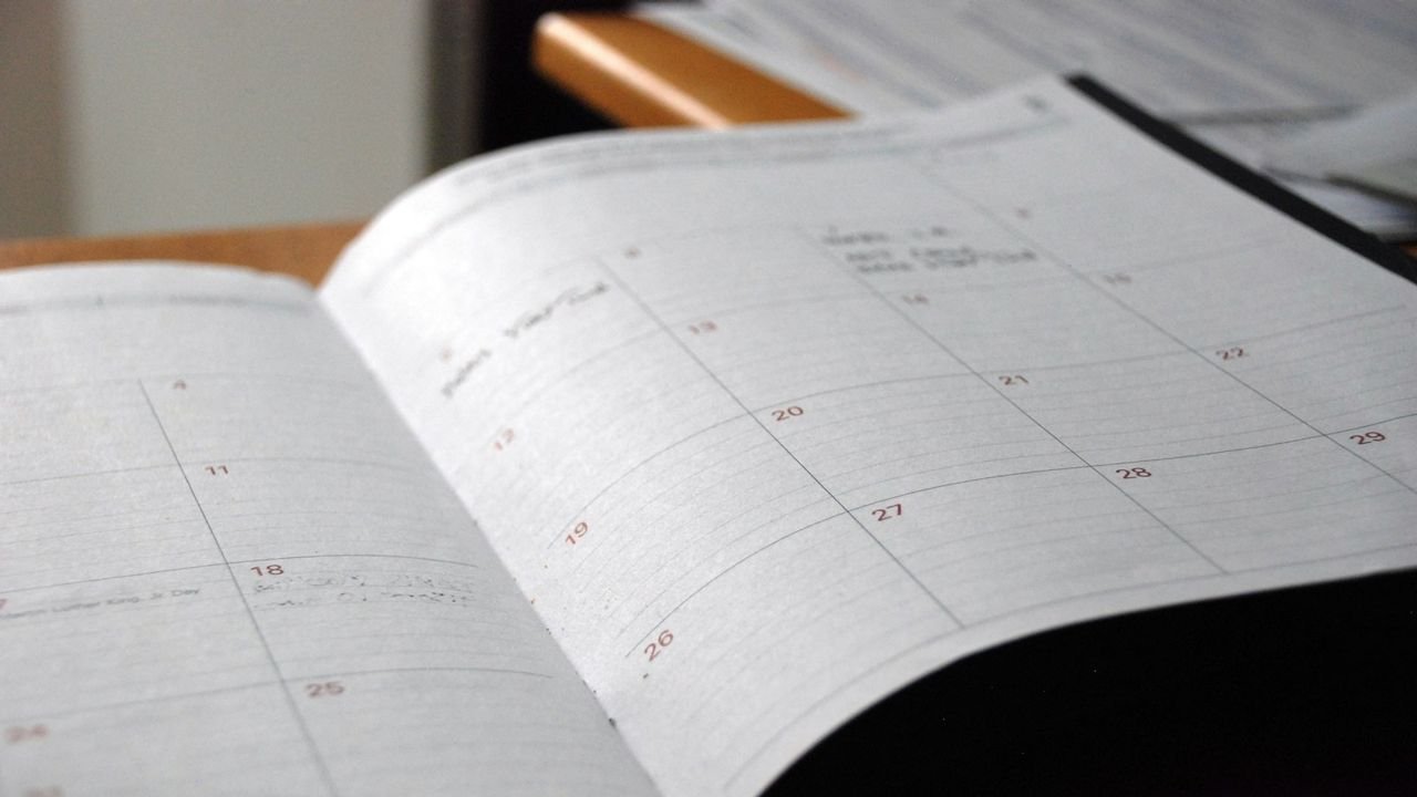 Open monthly planner on a wooden desk for scheduling clients