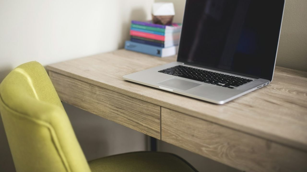 Laptop left open on a desk beside an empty chair