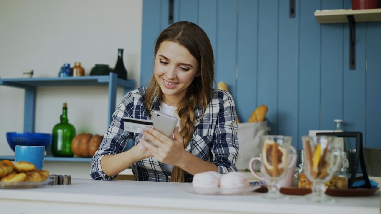 Smiling woman booking a service on her phone with a card in hand