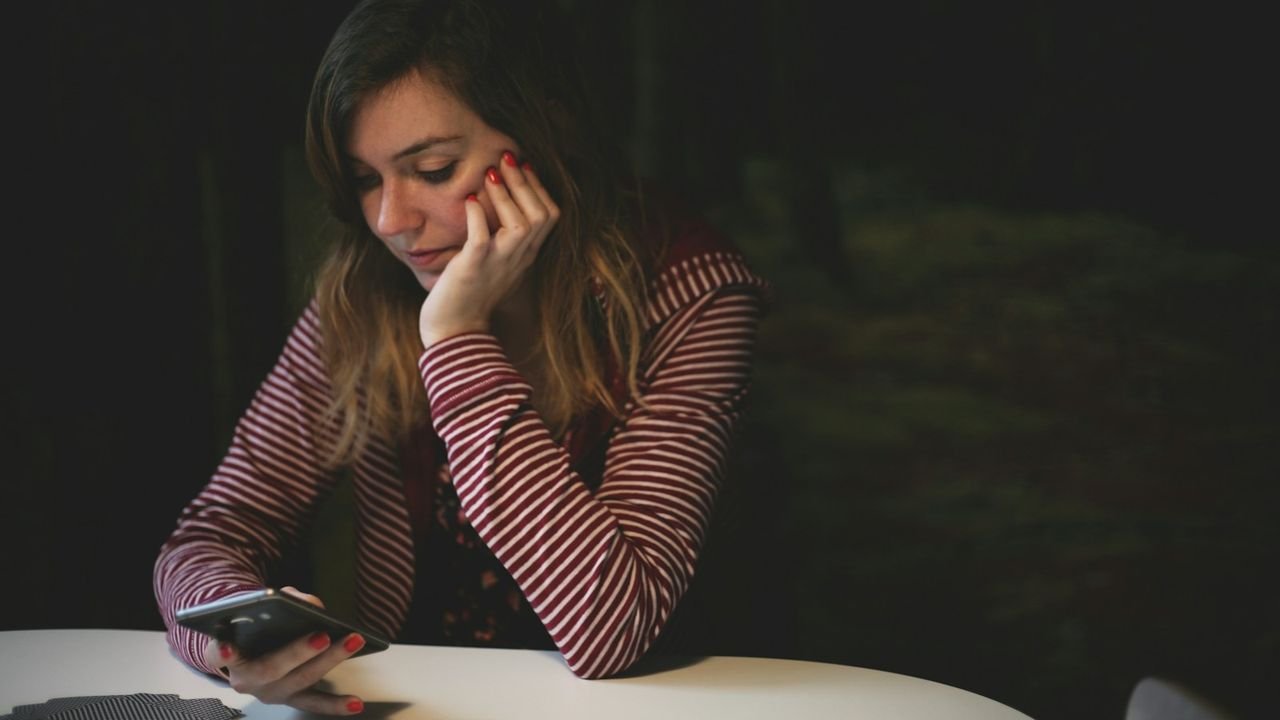 Woman leaning on a table waiting for a page to load on her smartphone