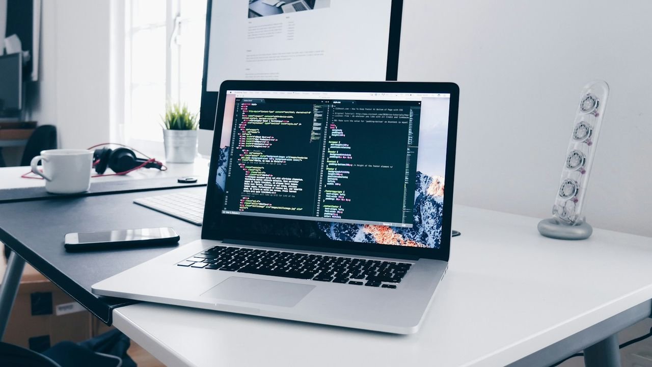 Laptop showing website code on a busy desk