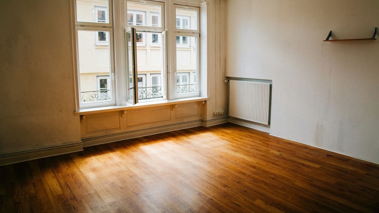 Empty room with a wooden floor and large window, ready for a move-out clean