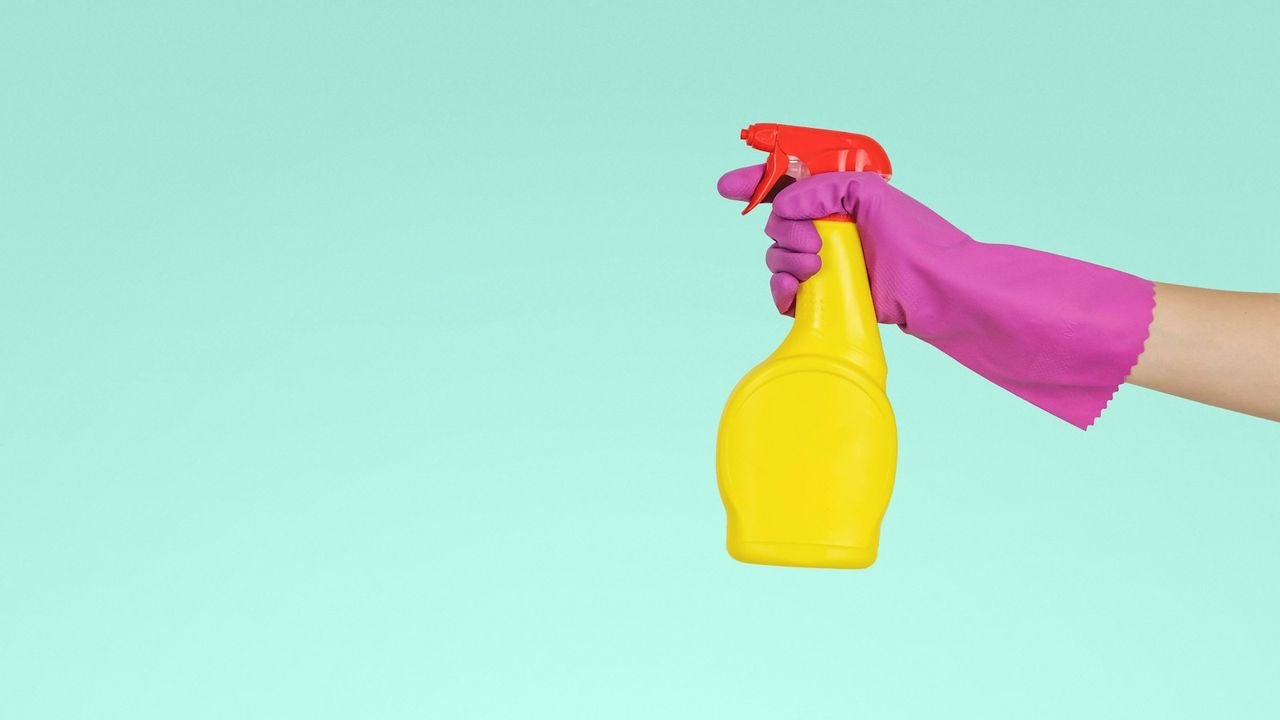 Cleaner holding a spray bottle, ready for a deep clean