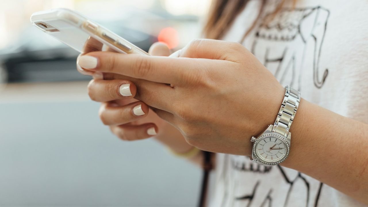Woman holding her phone to text or call a client